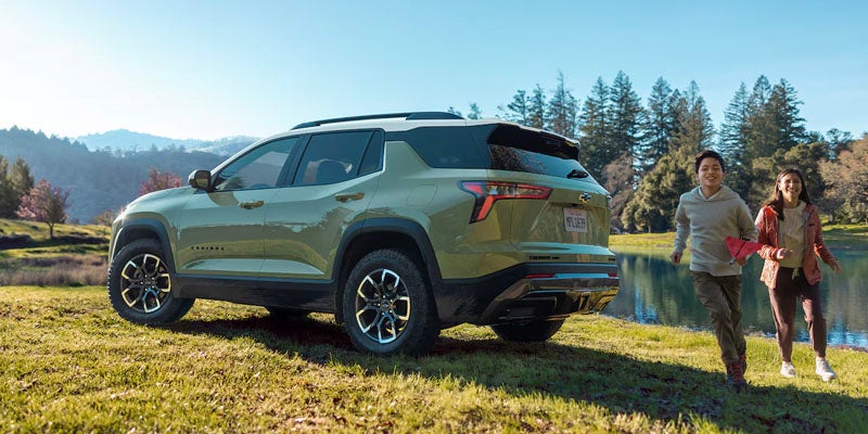 Chevrolet Equinox SUV parked near a scenic lake with passengers enjoying an outdoor adventure.
