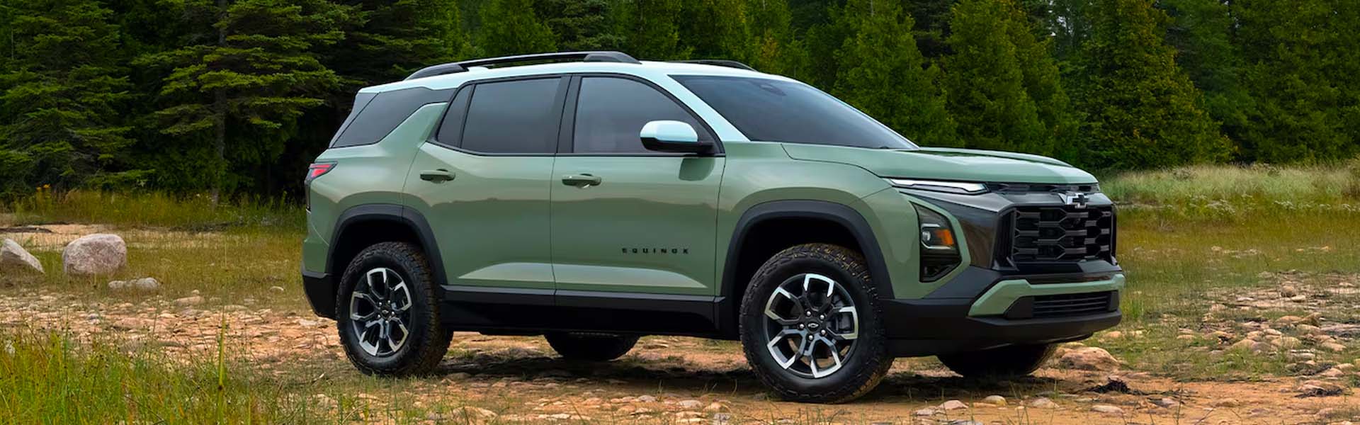 Chevrolet Equinox SUV parked on rugged terrain with a forest background showcasing its exterior design.