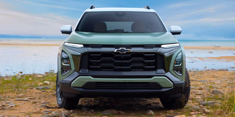 Chevrolet Equinox SUV front exterior view with bold grille design near a coastal landscape.