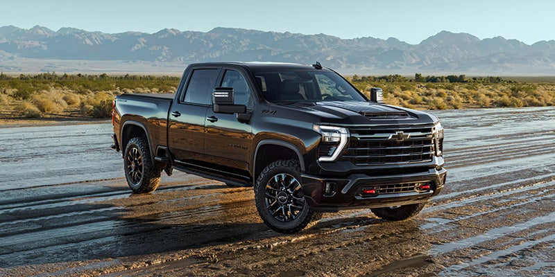 Chevrolet Silverado truck parked on rugged terrain with mountains in the background.